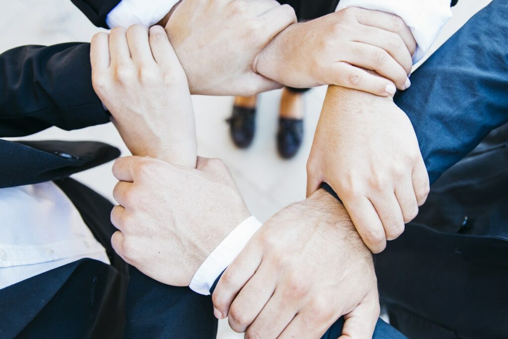 Six paires de mains d'un effectif commercial forment un cercle uni, symbolisant la force d'un esprit d'équipe solide. Les mains entrelacées illustrent la collaboration, la confiance et la cohésion au sein de l'équipe commerciale.